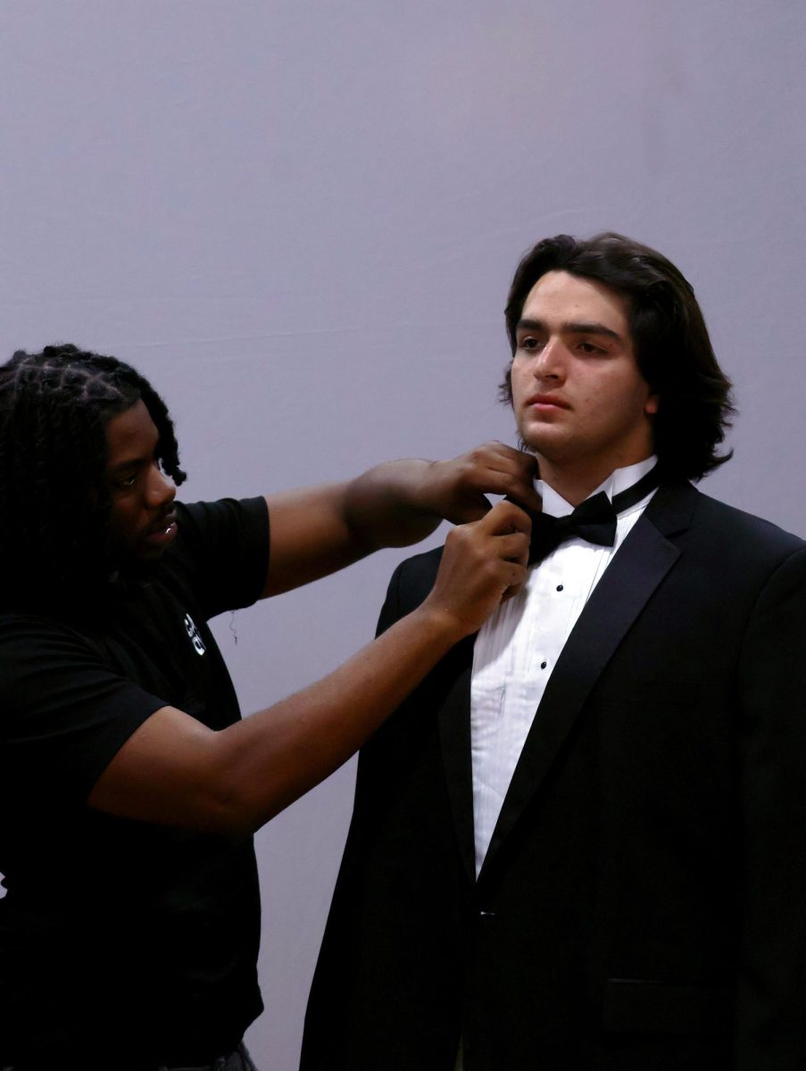 A CADY photographer adjusts the tie of a senior during his cap and gown session on Friday, Sept. 19. 