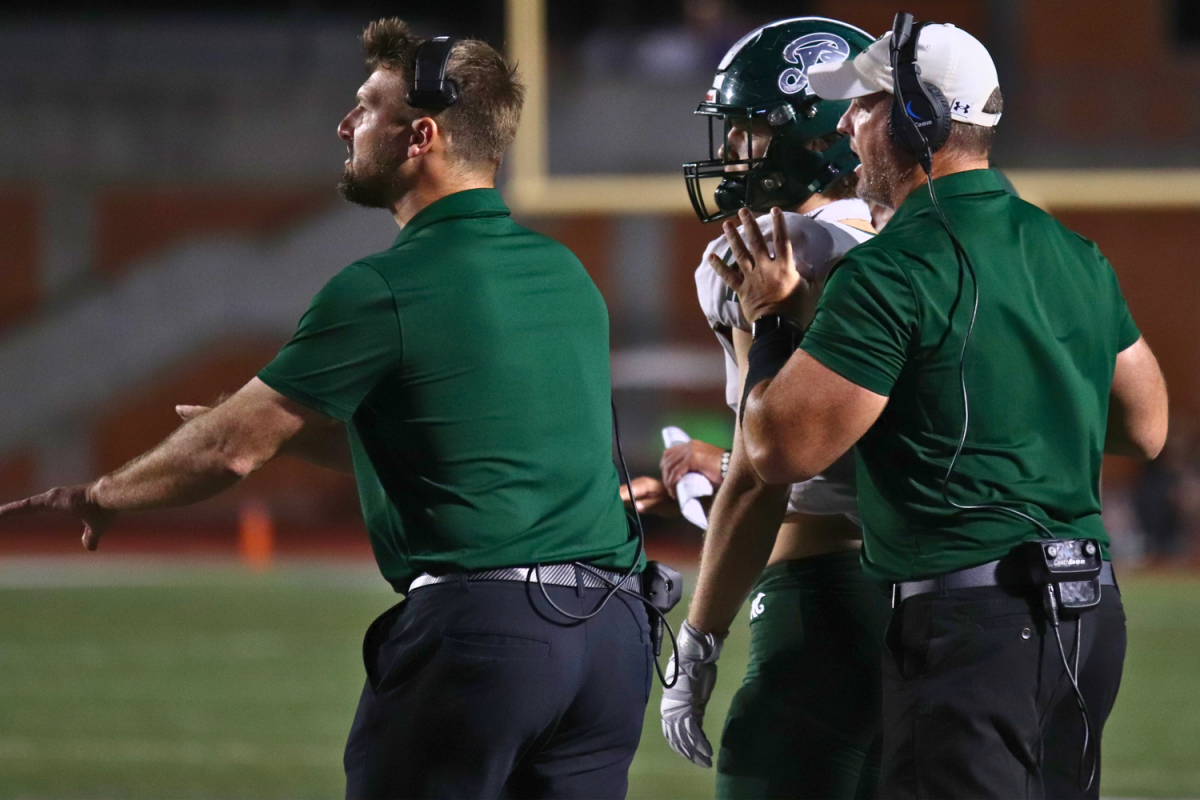 Coach Miller and Coach Mills on the sidelines watching the game with concentration and directing the players as needed.